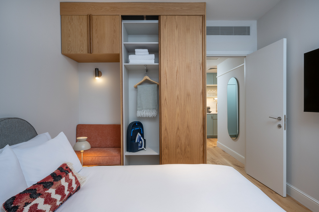 Comfortable and stylish bedroom in the One-Bedroom with Sofa Bed at master Mazeh Tel Aviv, featuring a plush bed and warm lighting.