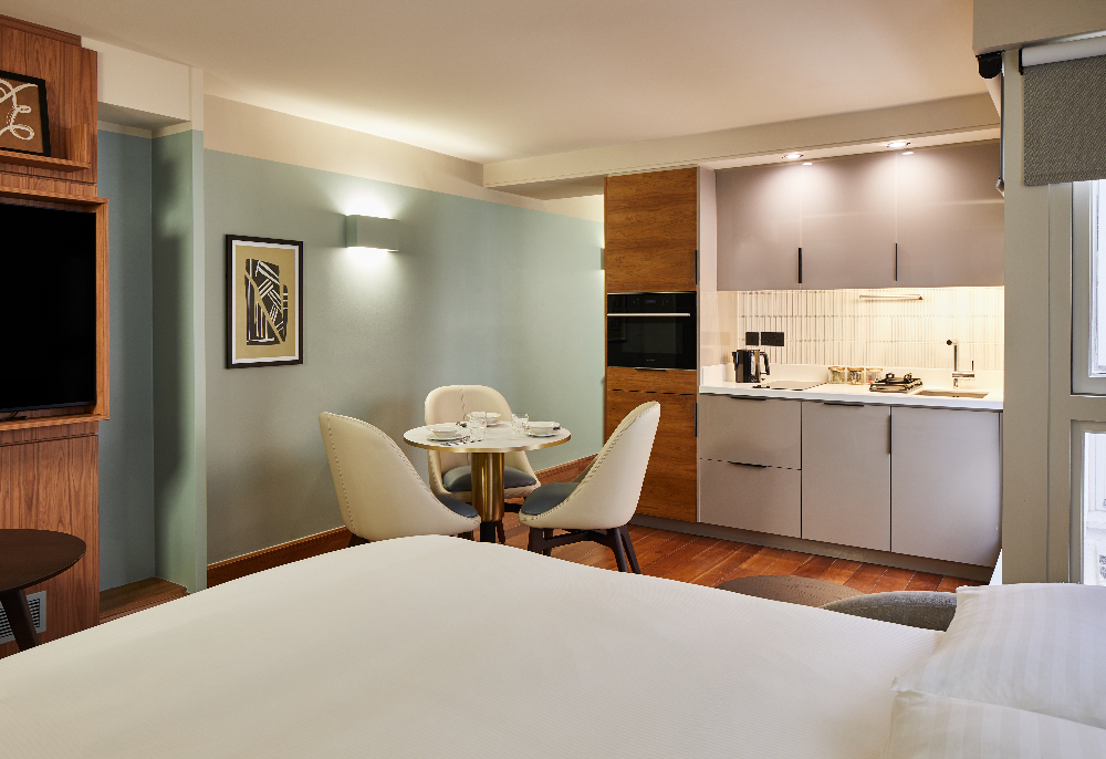 Inviting lounge space at master Farringdon London serviced apartments, with comfortable sofa, coffee table, and view of the compact modern kitchen.