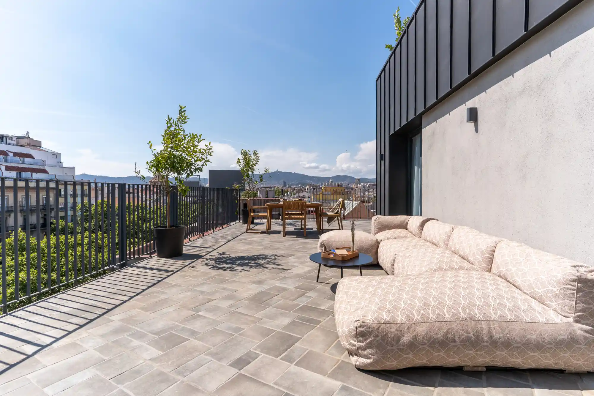Expansive private terrace with outdoor lounge and dining area, offering panoramic views of Barcelona from the One Bedroom Apartment at master La Rambla.
